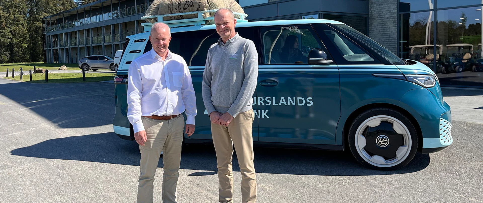 Områdedirektør fra Djurslands Bank Peter Møller og golfmanager Hans Knudsen fra Lübker Golf Resort står foran Djurslands Banks kaffebil med Lübker Golf Resort i baggrunden.