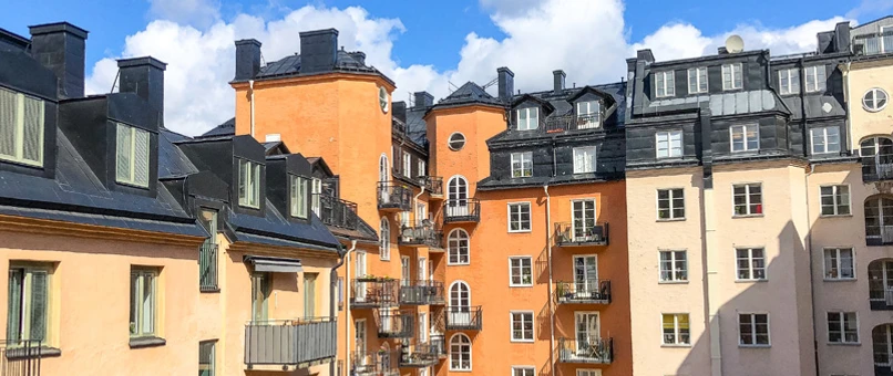 Et billede af flere boligblokke i forskellige farver med smukt solskin.