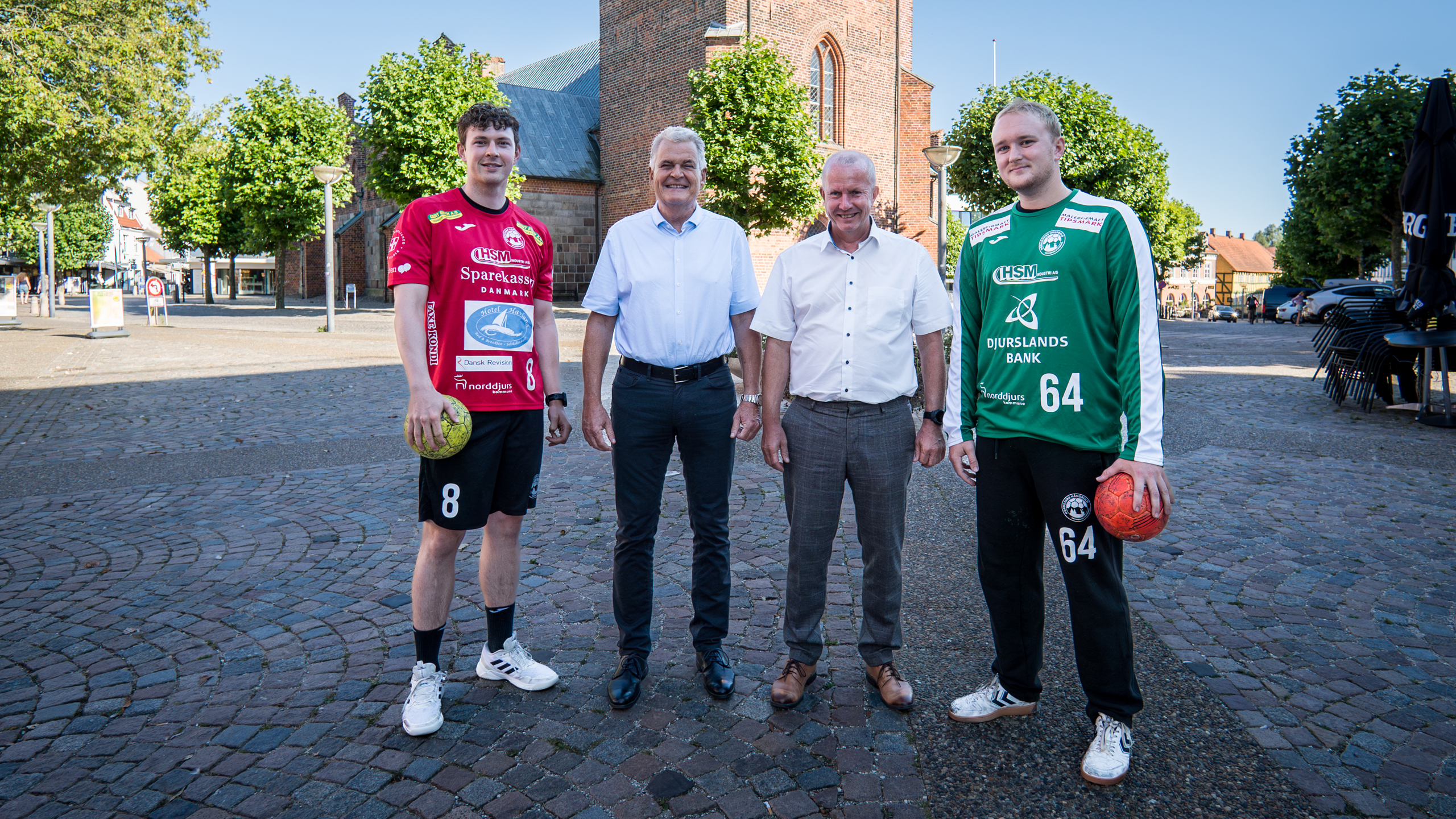 To håndboldspillere fra Norddjurs Håndbold står samme med områdedirektør Peter Møller fra Djurslands Bank og direktør Peter Lading Sørensen fra Sparekassen Danmark