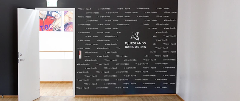 En væg i Djurslands Bank Arena med Djurslands Bank logo og teksten 