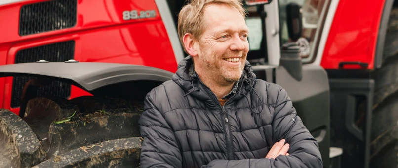 I forgrunden ses Anders Tækker, Landbrugschef i Djurslands Bank, i baggrunden ses en stor rød traktor.